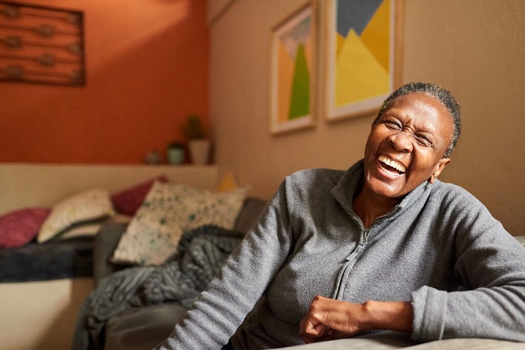Photo of a senior woman laughing on her couch