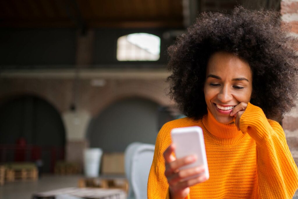 Photo of a woman smiling and looking at her phone