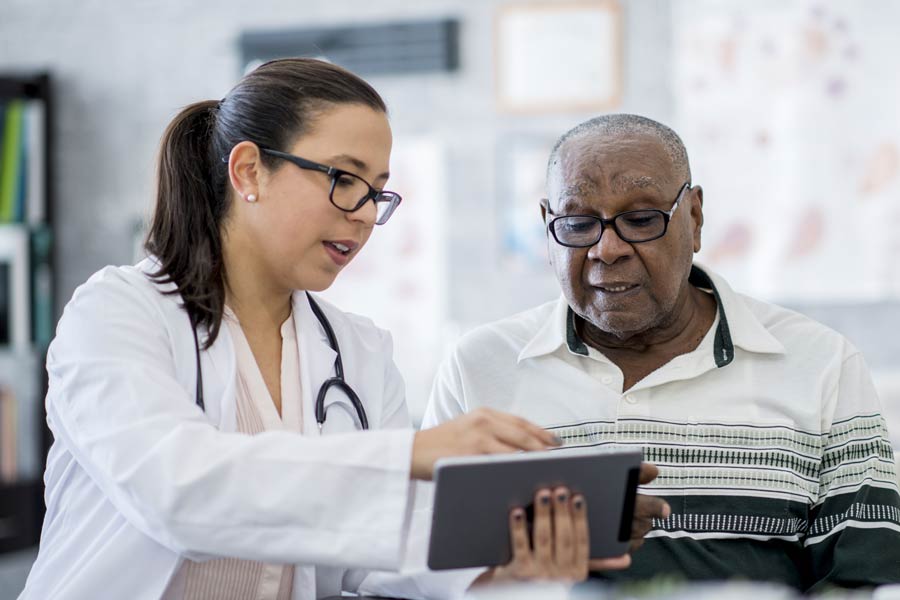 Photo of a man talking to his doctor while looking at a tablet